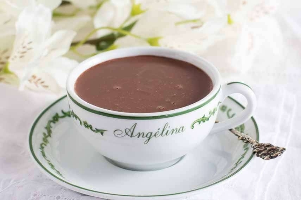 A cup of hot chocolate on a saucer decorated with flowers.