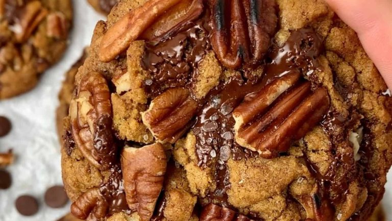 A hand holding a pecan-filled cookie.