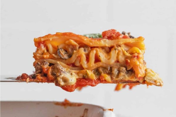 A piece of lasagna being lifted out of a dish.