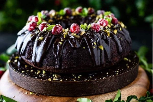 A chocolate Christmas bundt cake adorned with cranberries and pistachios.