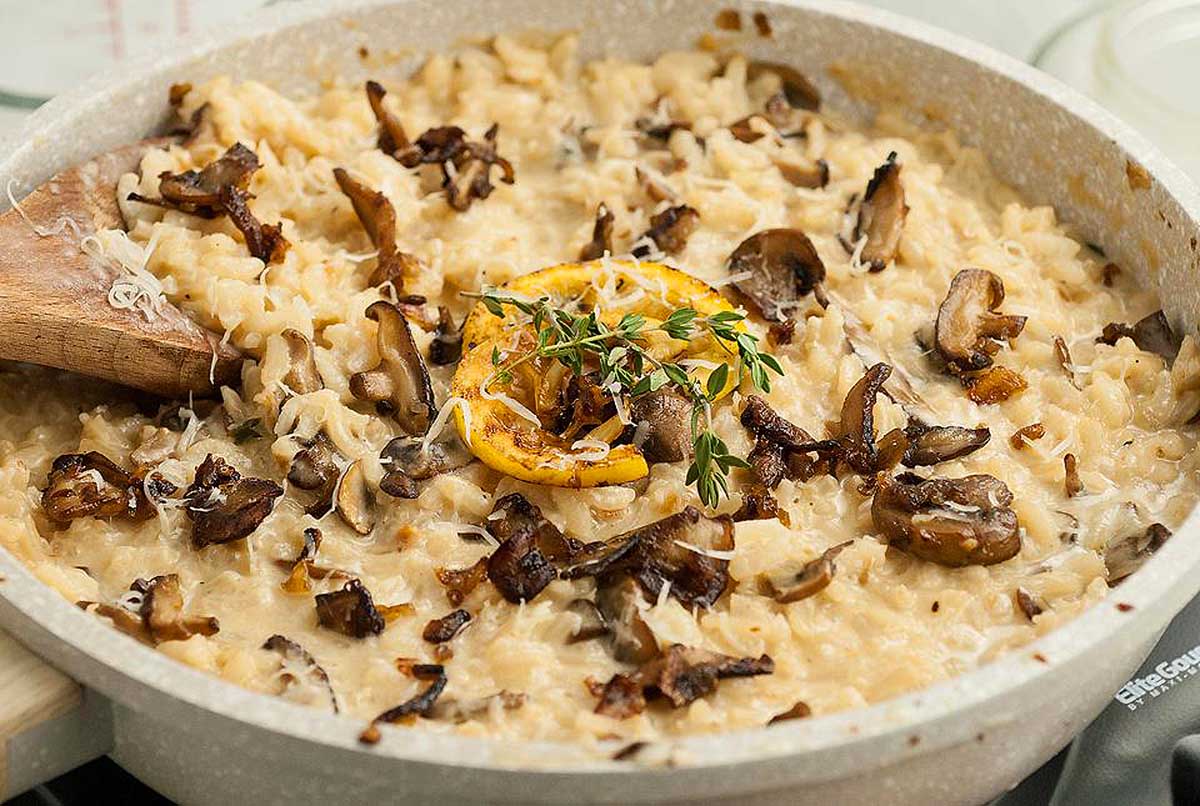 Mushroom risotto, a delicious dish perfect for any occasion, cooked in a pan with a wooden spoon.
