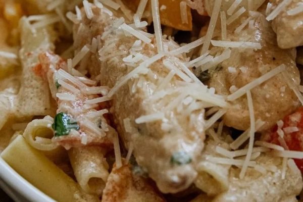 A delicious chicken pasta dish topped with flavorful tomatoes and grated parmesan cheese.