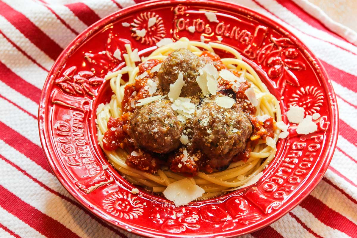 Warm and satisfying spaghetti and meatballs, a comforting winter dinner, served on a red plate.
