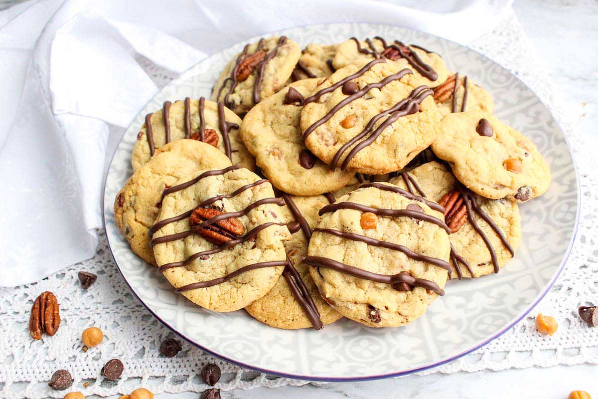 Chocolate pecan cookies on a plate with chocolate drizzle.