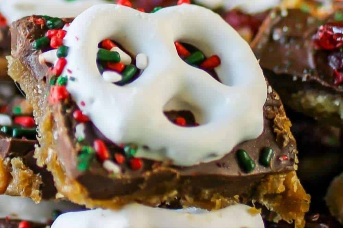 A close up of Christmas bark, chocolate pretzel bars with icing and sprinkles.