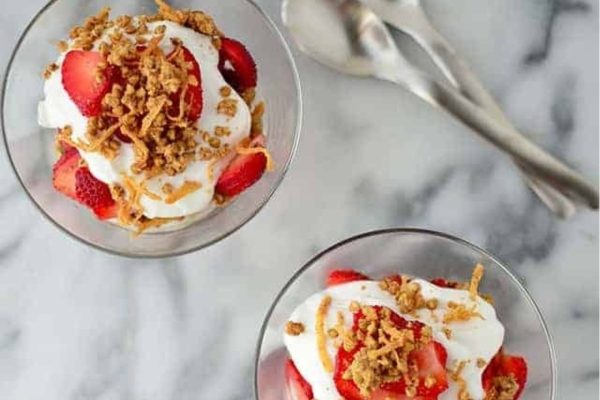 Two dessert bowls with strawberries, granola, and coconut.