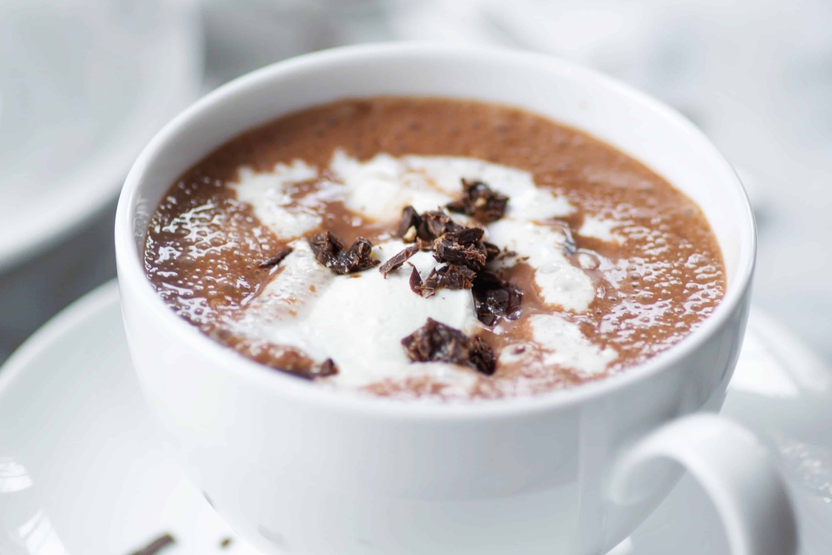 A cup of hot cocoa with whipped cream and chocolate chips.
