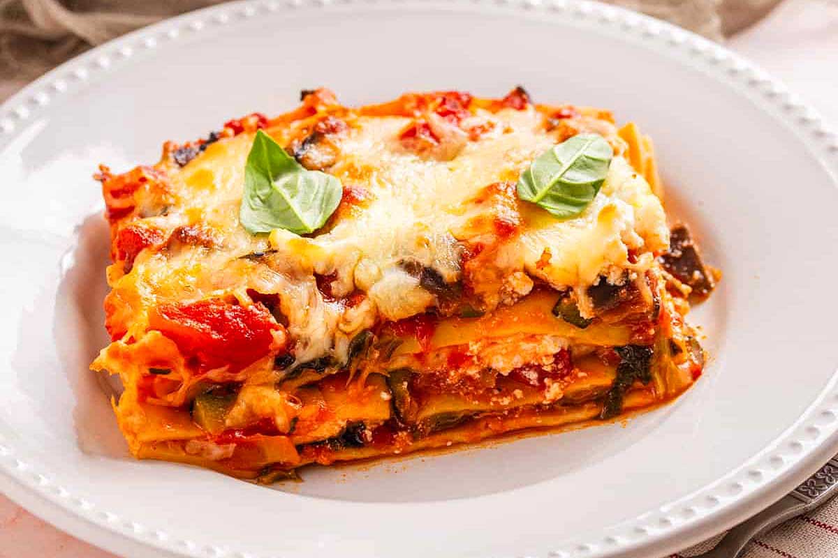 A plate of lasagna with tomatoes and basil.