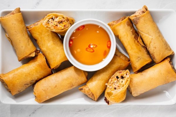 Vietnamese spring rolls with dipping sauce on a white plate.