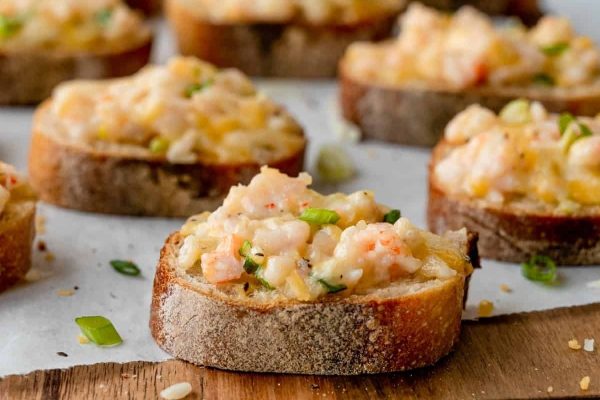 Asian-inspired shrimp and cheese crostini elegantly displayed on a cutting board.