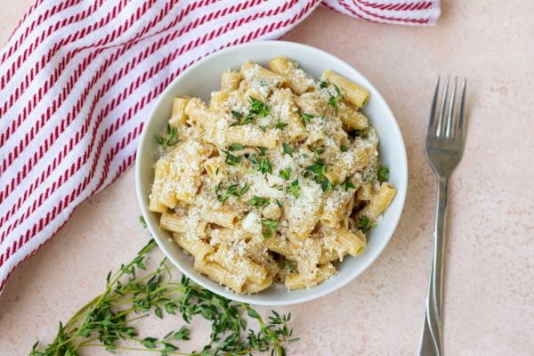 A bowl of kid-friendly pasta with parmesan cheese and thyme that parents love.