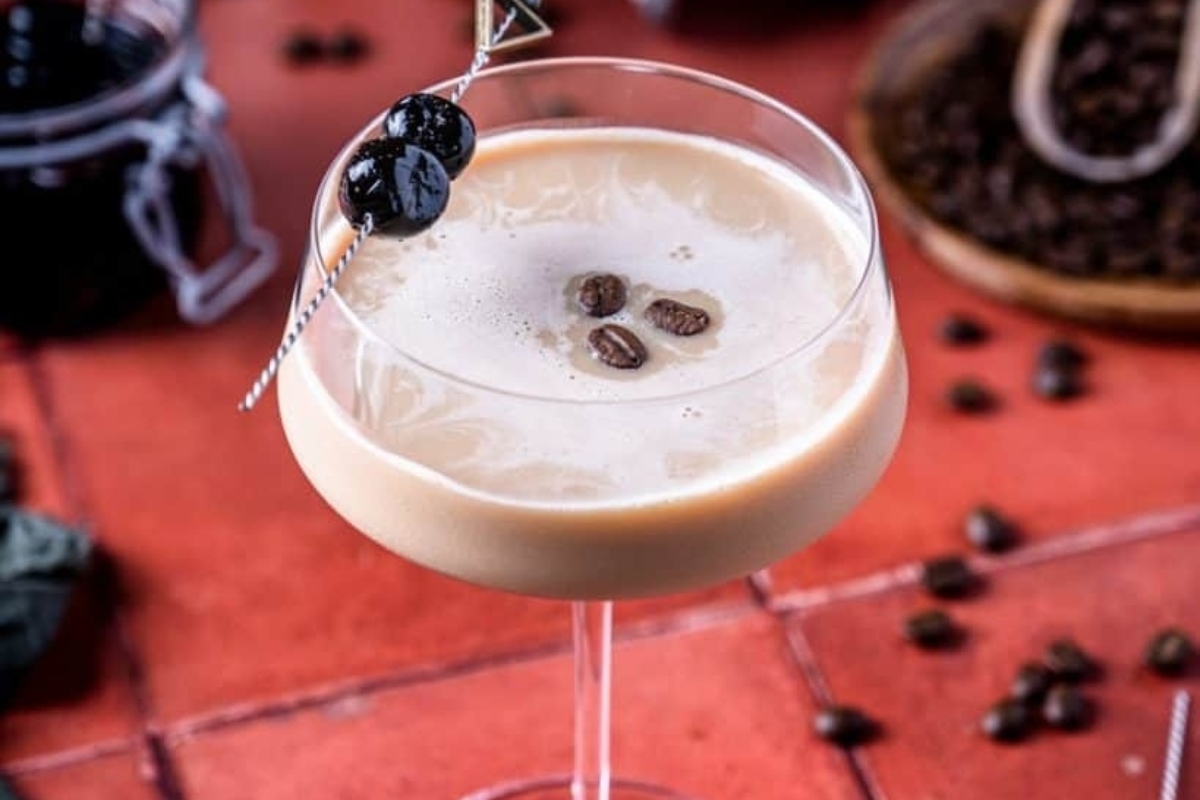 A martini recipe with coffee beans and olives in a glass.