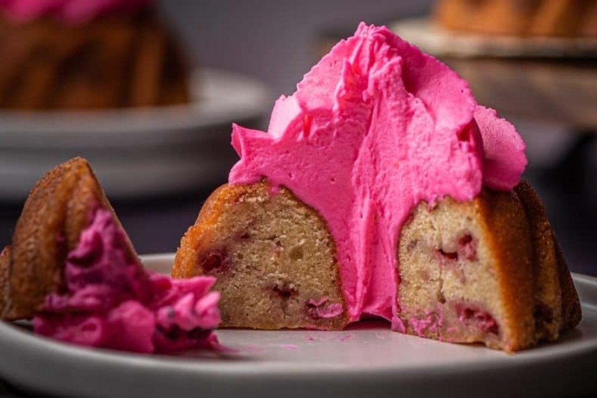 A pink bundt cake recipe with a bite taken out of it.
