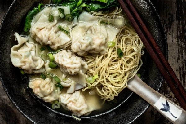 Asian dumplings and noodles in a bowl with chopsticks.