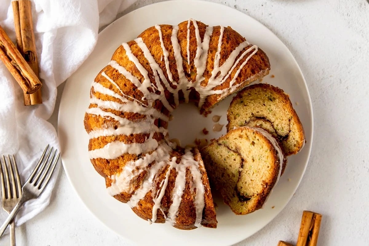 A cinnamon-spiced Bundt cake with a drizzle of icing on a plate.