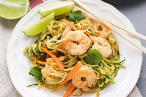 Zucchini shrimp noodles on a white plate with chopsticks.