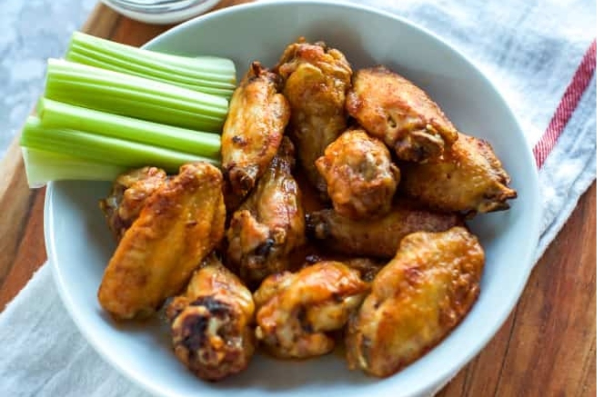 Delicious chicken wings served in a white bowl with crispy celery.