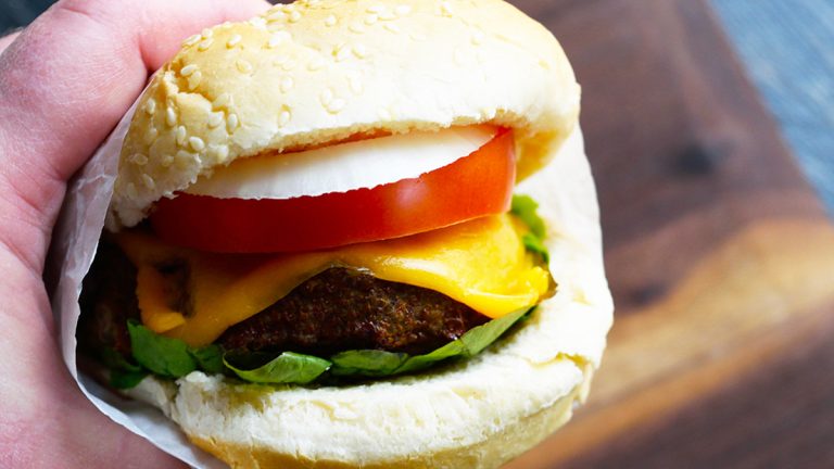 A person holding an air fryer turkey burger.