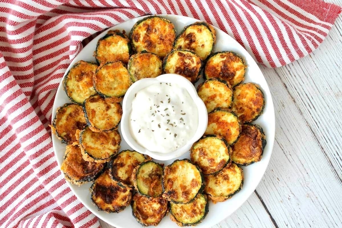 Zucchini fries with dipping sauce on a white plate.