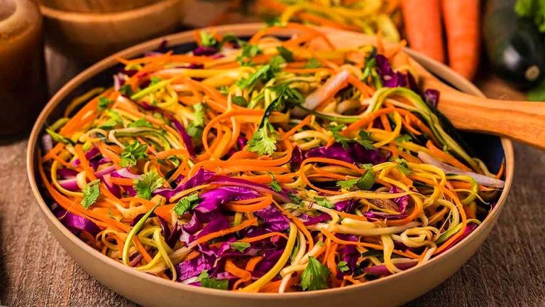 A bowl of Asian slaw with carrots, cabbage, and zucchini.