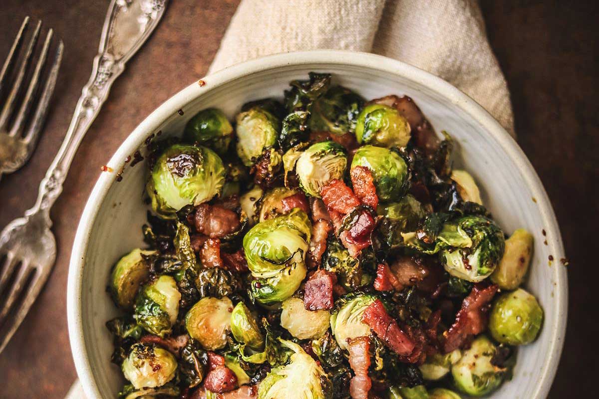 Brussels sprouts with bacon and kale in a white bowl.