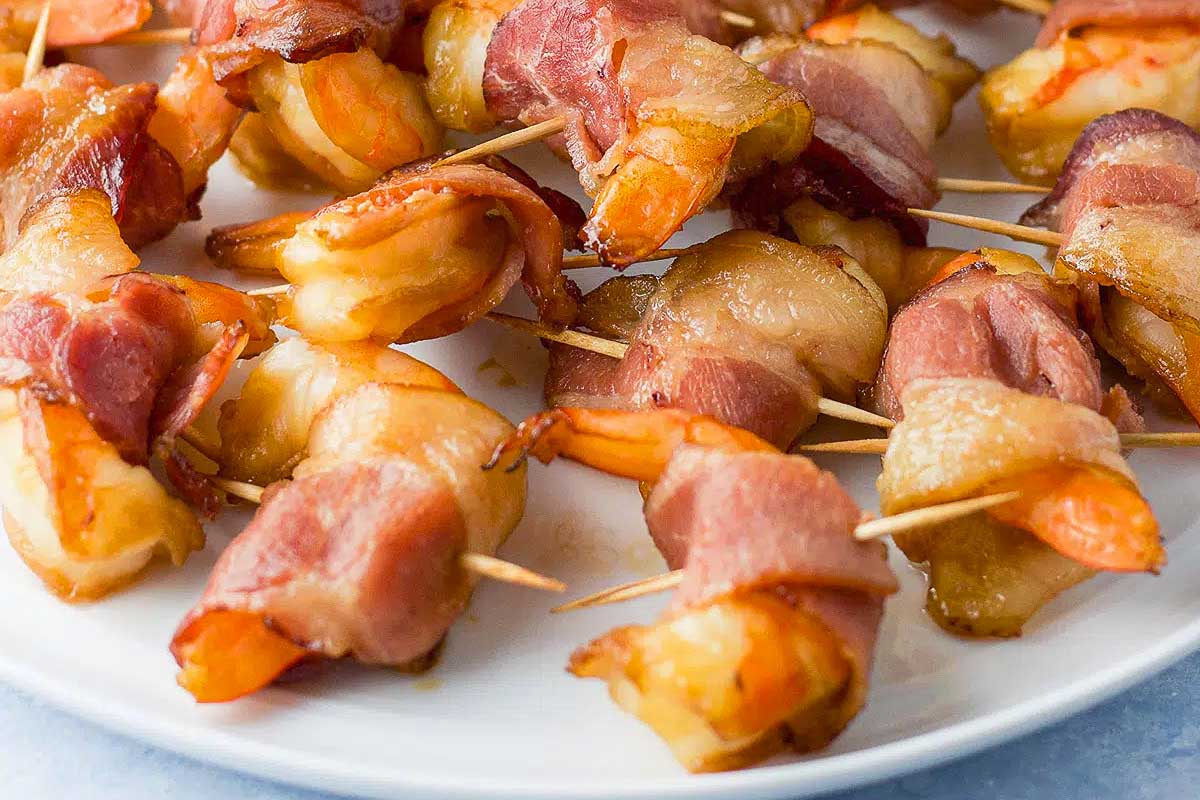 Bacon wrapped shrimp skewers on a plate.