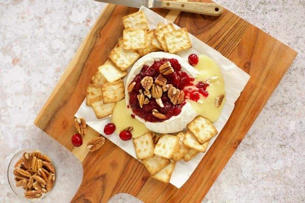 A cheese platter with crackers and cranberry sauce.