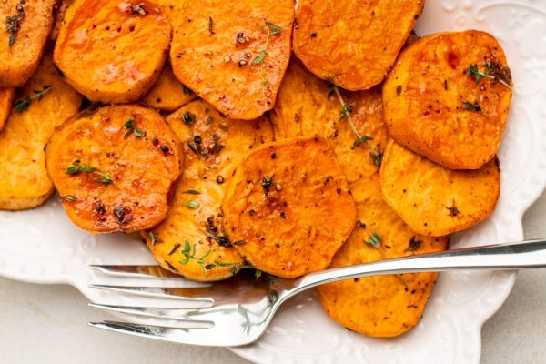 Roasted sweet potatoes on a plate with a fork, perfect for Thanksgiving.