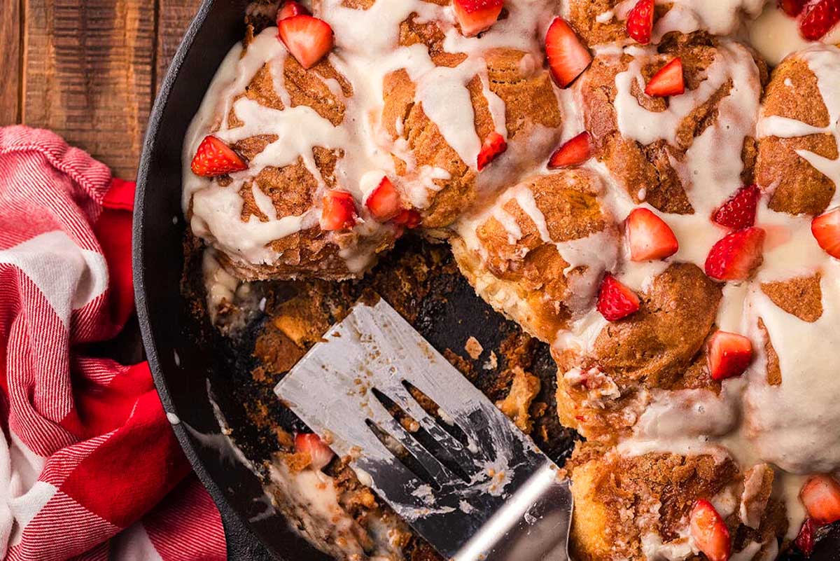 A skillet with strawberries and icing on it.