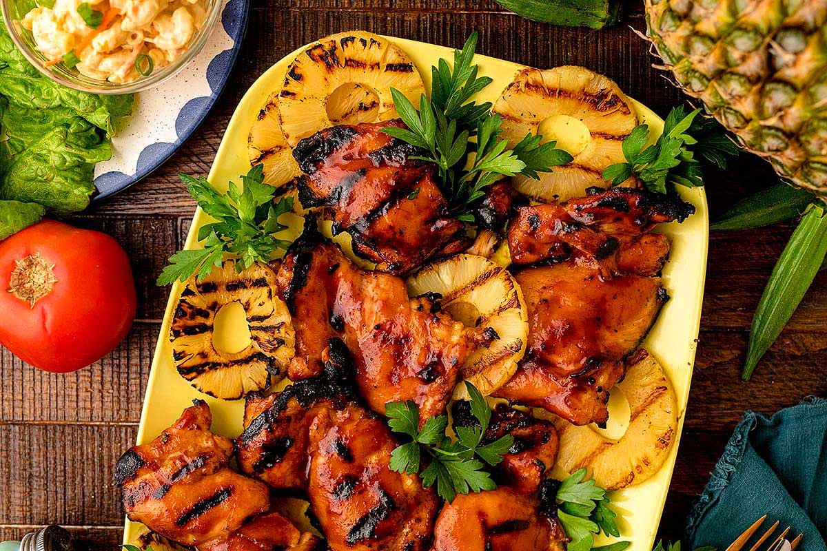 Inspired by Hawaiian cuisine, this luau-themed dish features succulent grilled chicken served on a plate adorned with sweet pineapples and crisp vegetables.
