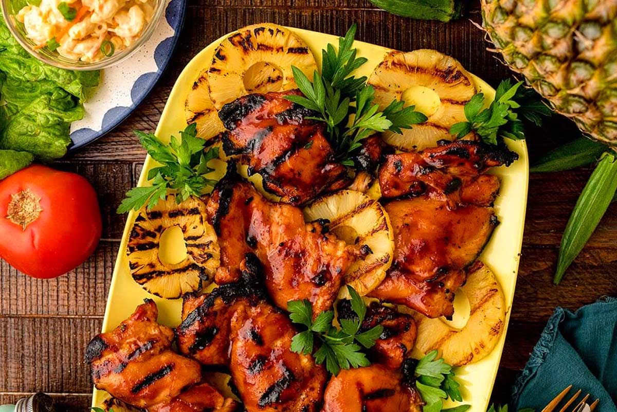 A mouthwatering Hawaiian grilled chicken dish, bursting with flavors of succulent meat, served on a plate adorned with juicy pineapples and vibrant tomatoes. Perfect for a romantic date night.