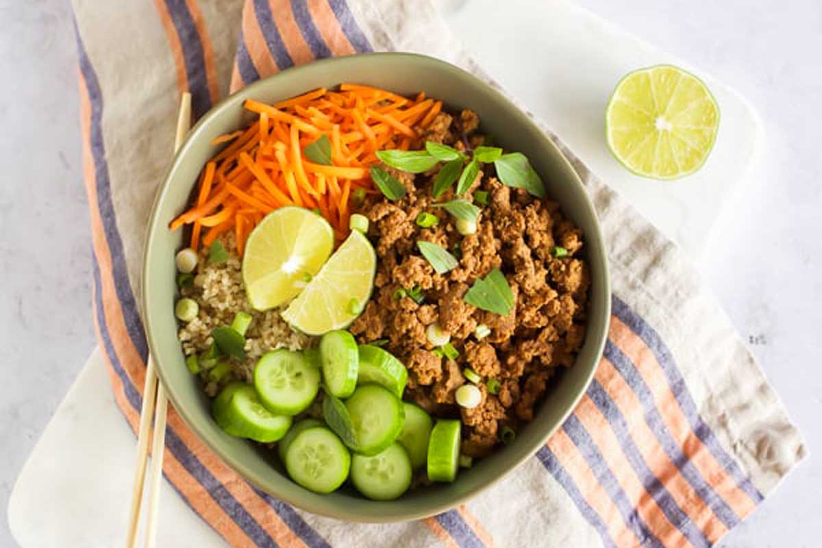 A bowl of asian meatballs with carrots and cucumbers.