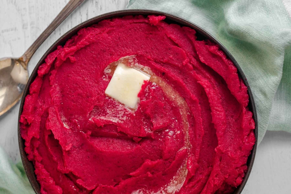 Beetroot mashed potatoes, a perfect side dish to complement roast beef, served in a bowl with a dollop of butter.