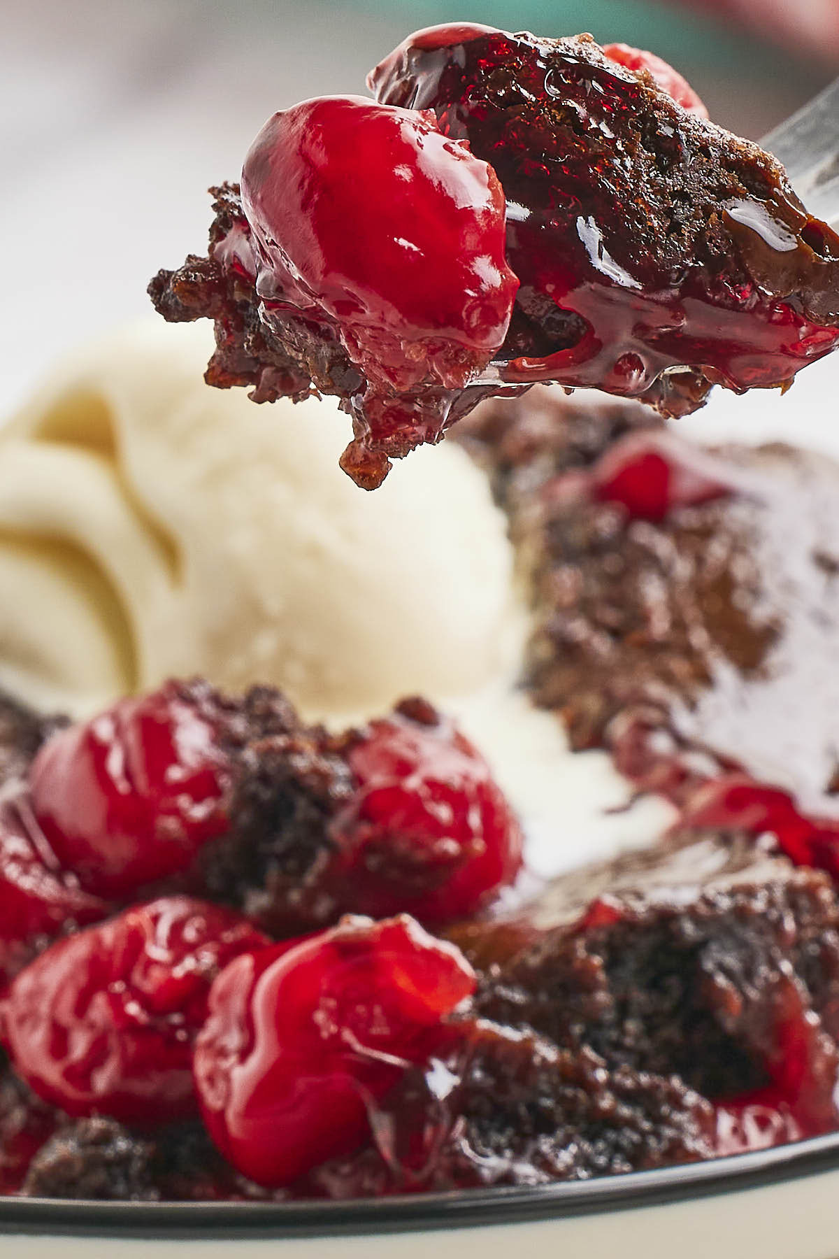 Chocolate dump cake with cherries and ice cream on a plate, perfect for indulging in a delightful dessert.