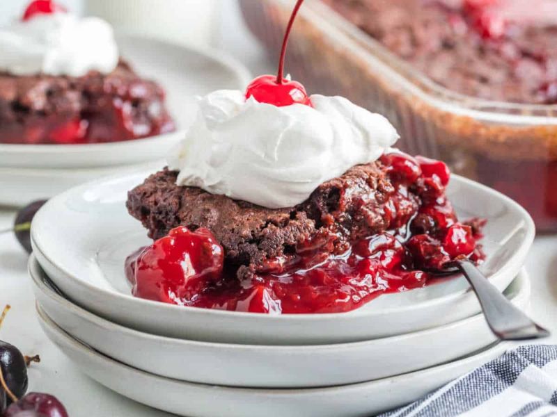 black forest dump cake with whipped cream and cherry.