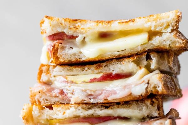 A stack of grilled cheese sandwiches with Brie and ham.