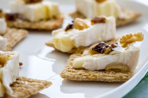 Brie cheese crackers with walnuts on a plate.
