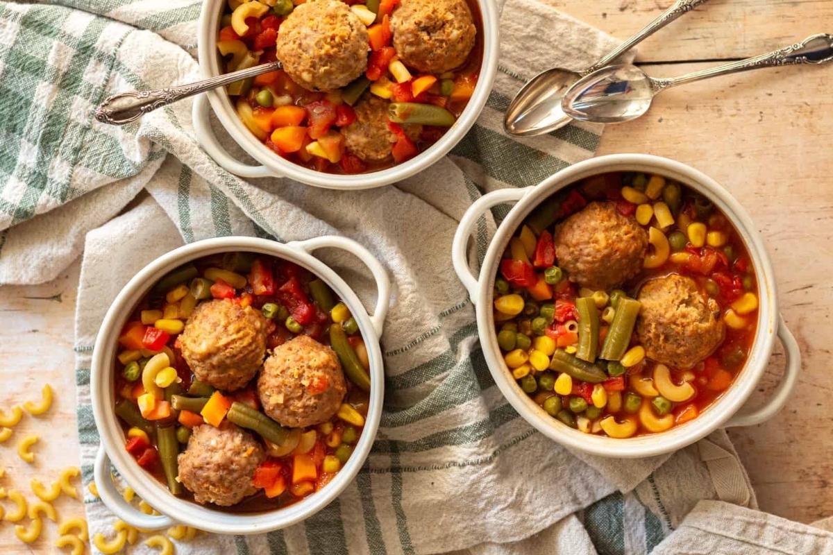 Three bowls of meatballs and vegetables, including frozen mixed vegetables, on a table.