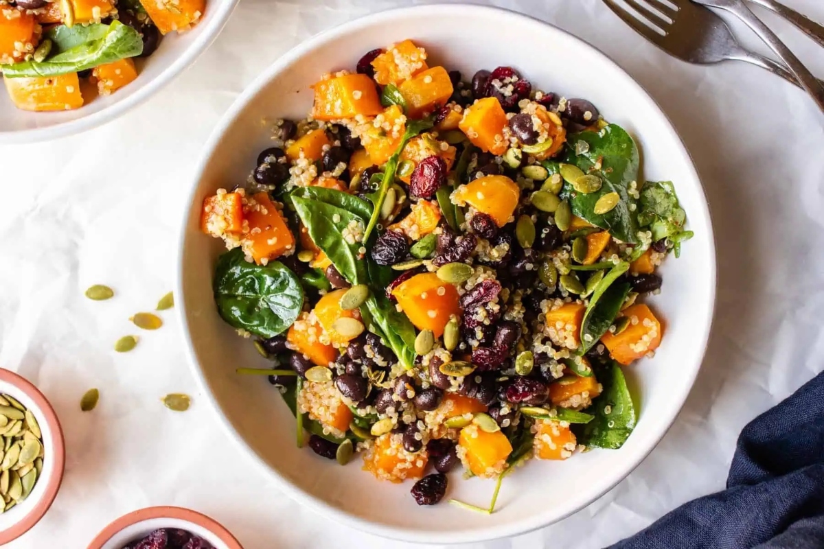 A bowl of squash salad with black beans and pumpkin seeds.