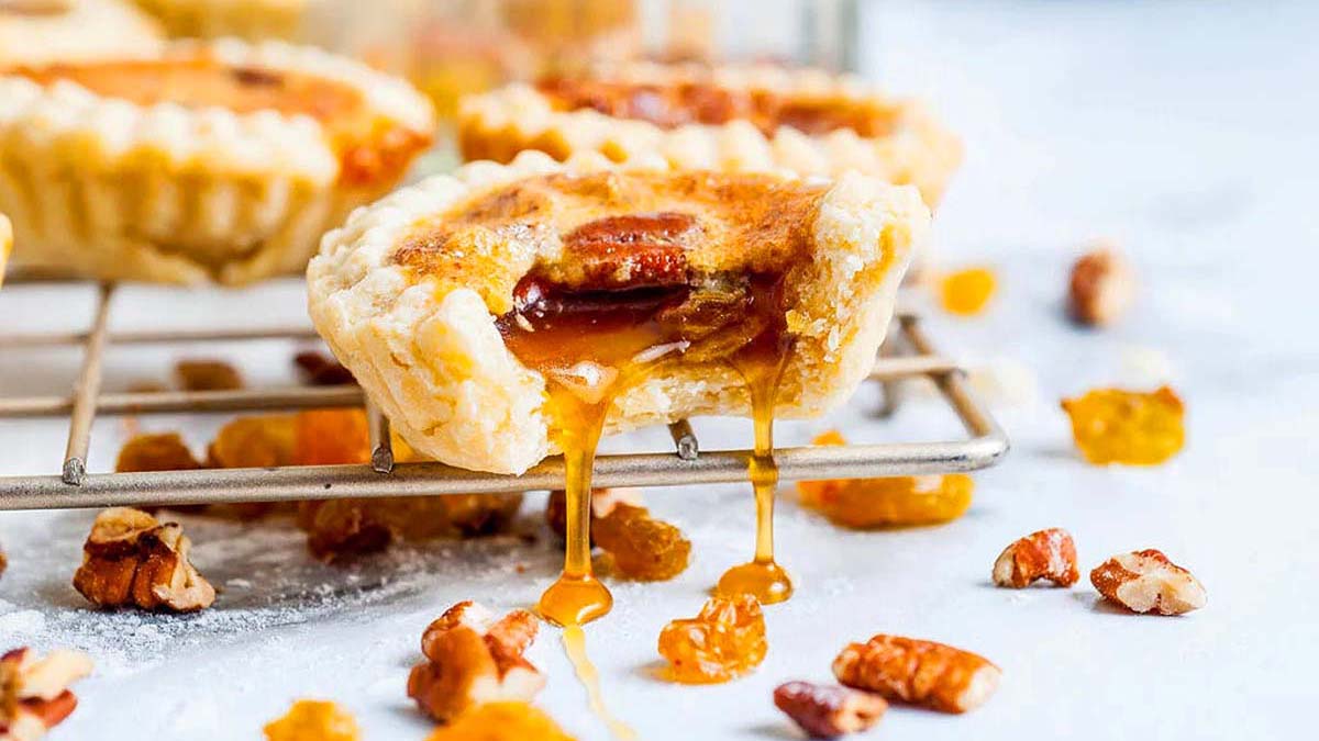 Pecan pies on a cooling rack with a drizzle of caramel - the ultimate pecan recipe.