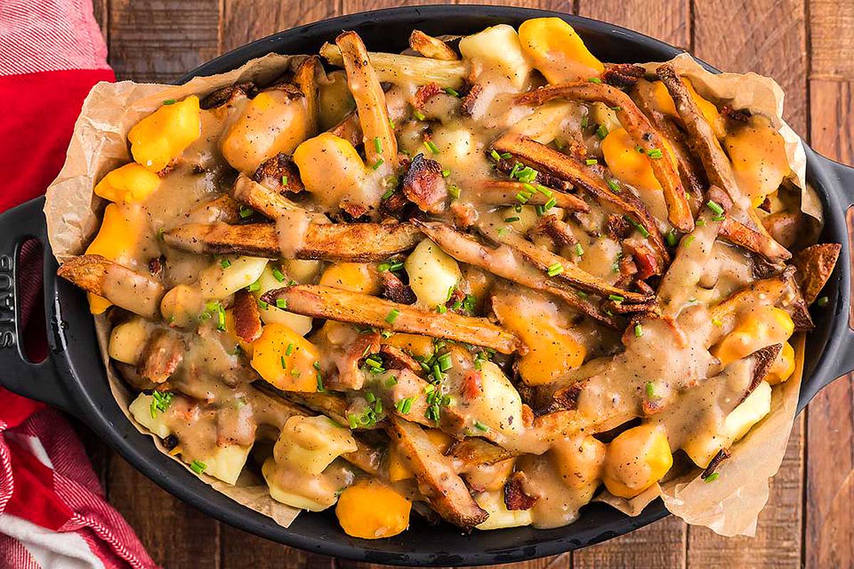 A hearty skillet of pub food, mouthwatering potatoes smothered in rich gravy.