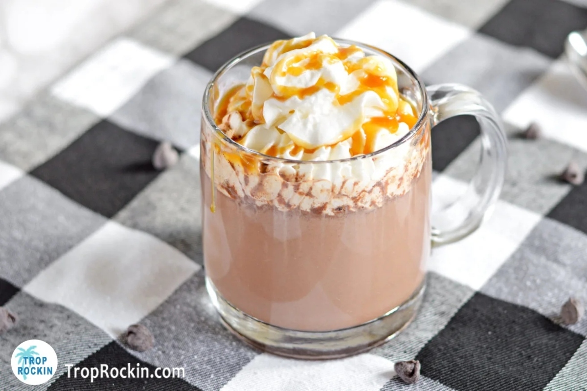A creamy cup of hot chocolate, indulgently topped with caramel drizzle and a generous dollop of fluffy whipped cream.