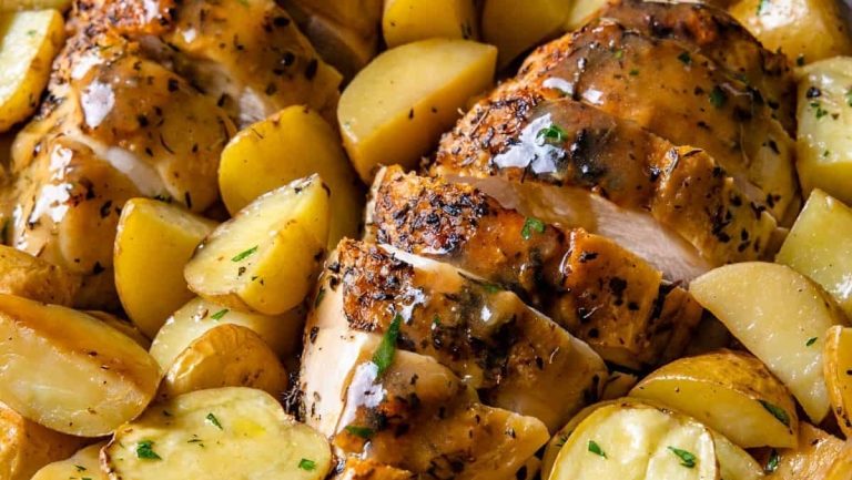 Bone-in chicken breasts with potatoes and gravy in a skillet.