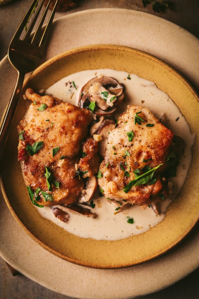 Champagne chicken breasts with mushroom sauce on a plate with a fork.