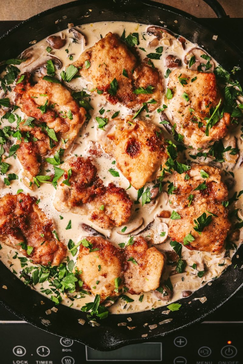 Champagne chicken breasts in a skillet with mushrooms and herbs.