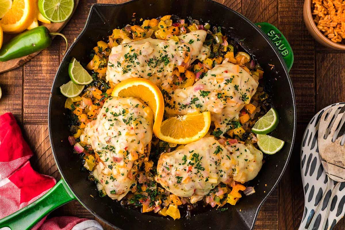 Mexican chicken in a skillet with oranges and limes.