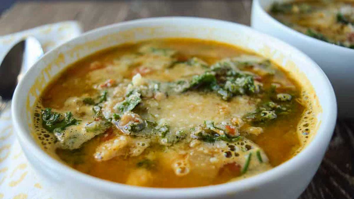 Two bowls of soup with spinach and cheese.