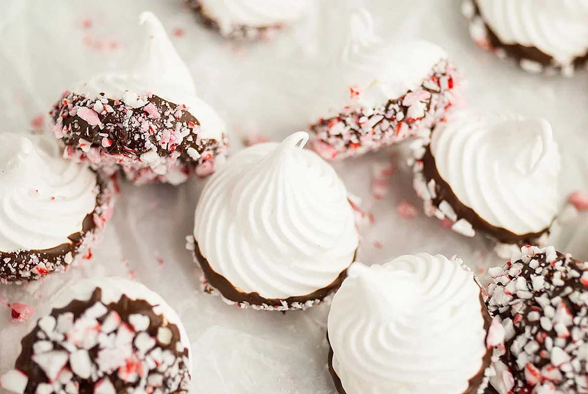 Candy cane chocolate peppermint meringue cookies with white icing and sprinkles.