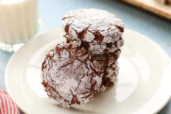 Chocolate crinkle cookies on a plate next to a glass of milk.