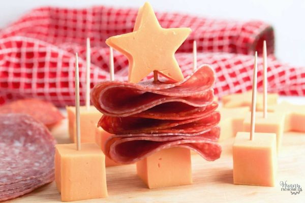 A charcuterie board adorned with a festive arrangement of meat and cheese sticks, resembling a Christmas tree.